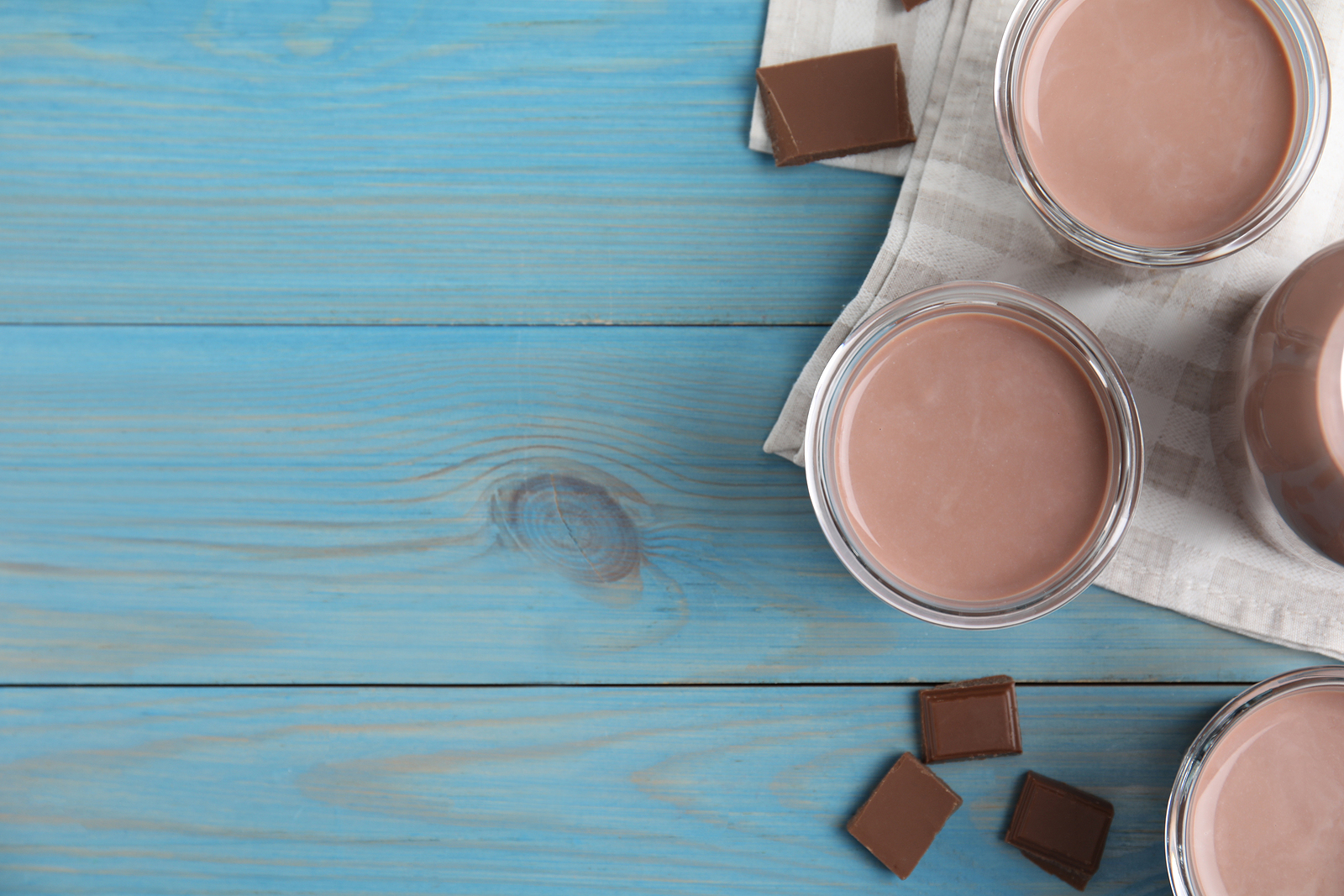 A glass of chocolate milk on a blue woodgrain background.