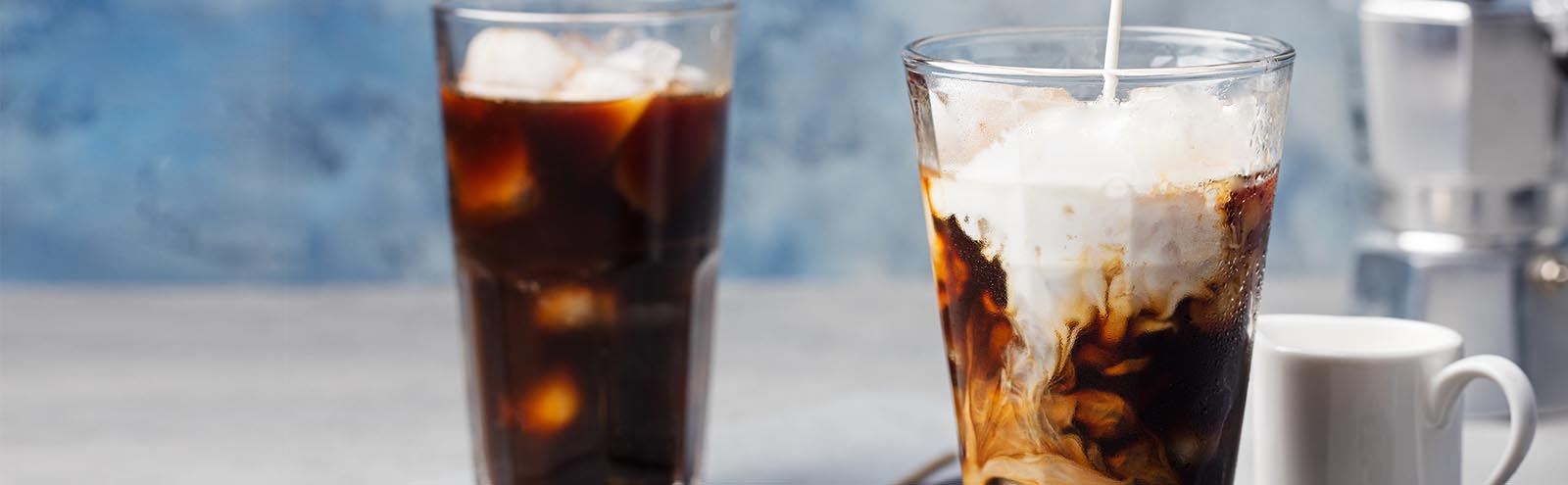 Two glasses with creamer being poured into them.